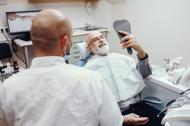 odontogeriatria idoso sorrindo para um espelho na clinica odontologica