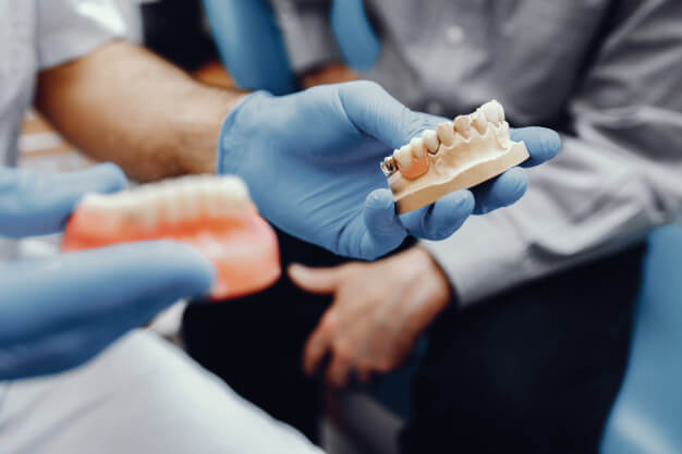 odontogeriatria medico mostrando dentadura para o paciente idoso