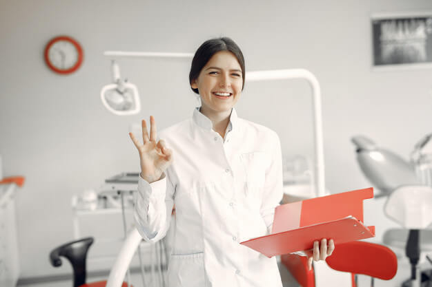 carimbo de dentista mulher com jaleco branco sorrindo com a mao para cima