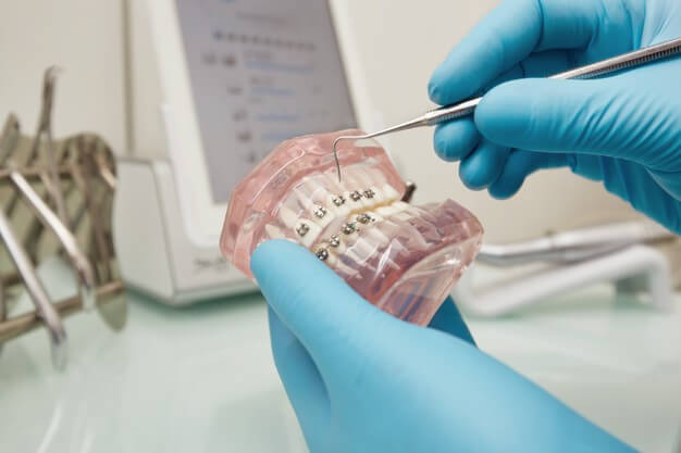 dentista organizado mexendo com instrumento odontologico em prototipo de dente