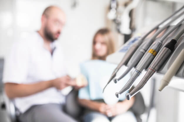 CRO equipamento odontologico e no fundo dentista conversando com paciente