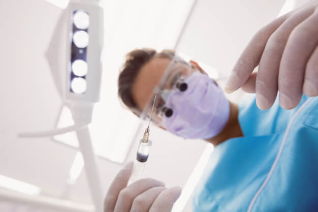 sedação consciente dentista com seringa na mão equipamento de proteção nos olhos