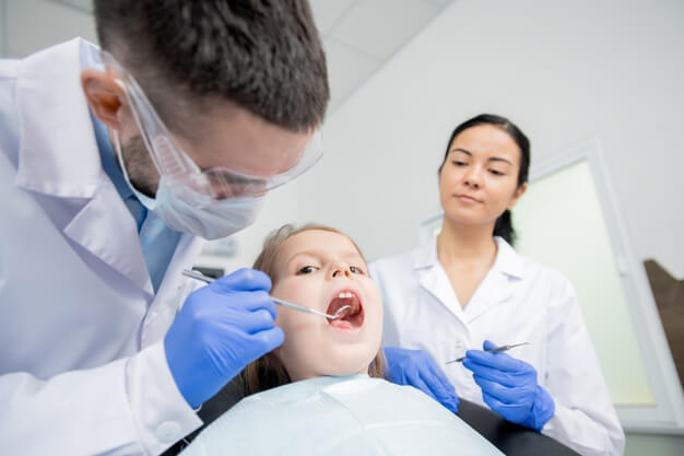 auxiliar de saúde bucal e dentista atendendo criança