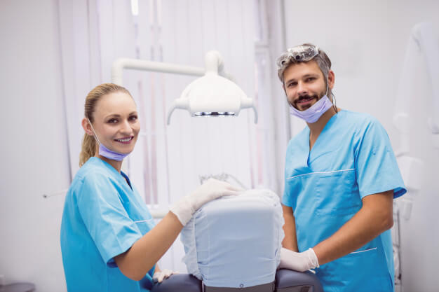 dentista e auxiliar de saúde bucal sorrindo